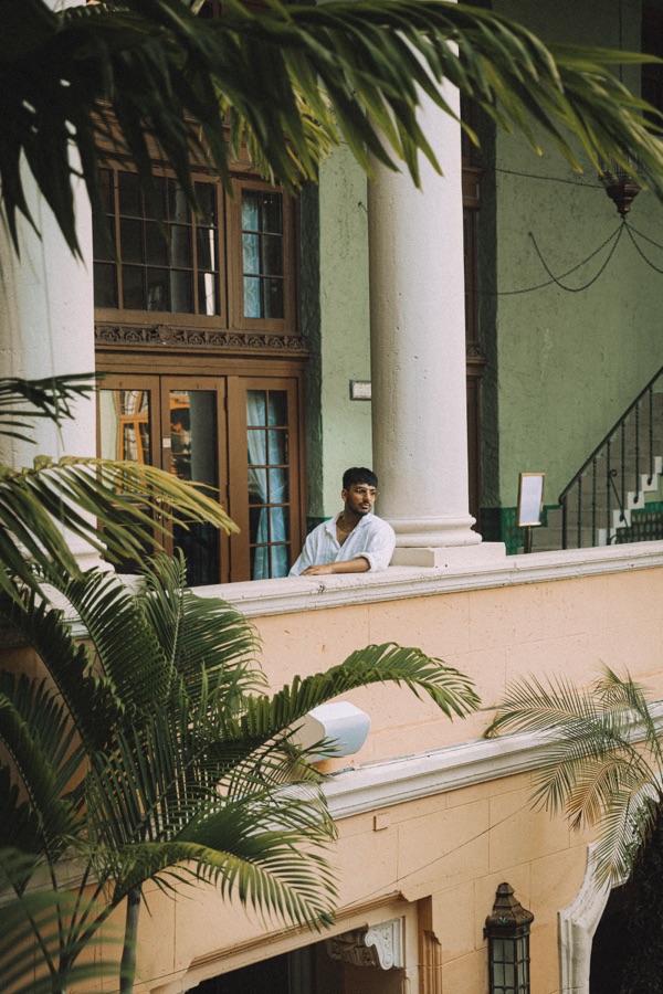 A figure on a balcony framed by palms in Miami